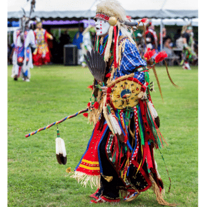 performers wearing vibrant traditional attire perform a dance at a 4th of July powwow, while spectators watch.