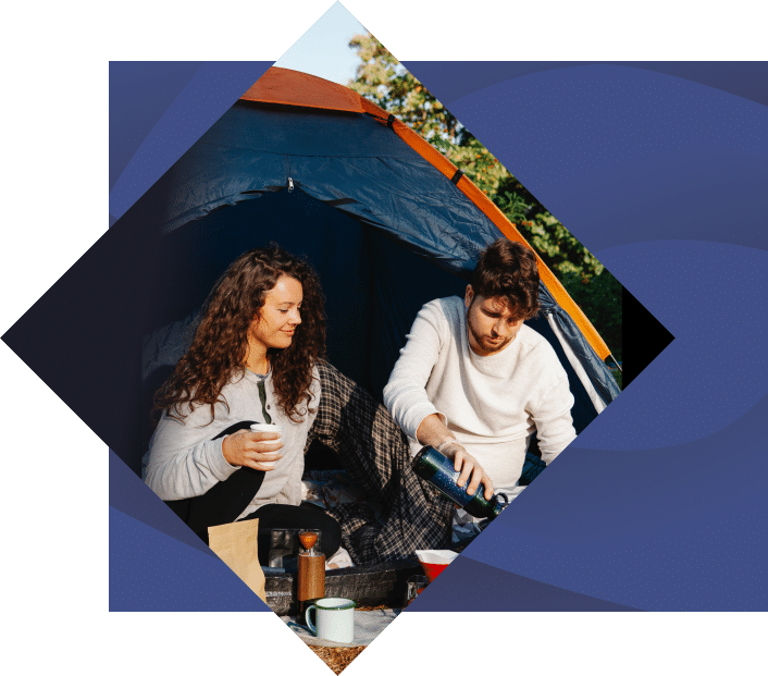 couple after waking up in a tent in the morning drinking coffee