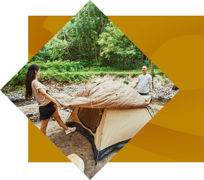 couple setting up a tent for camping with trees in the background