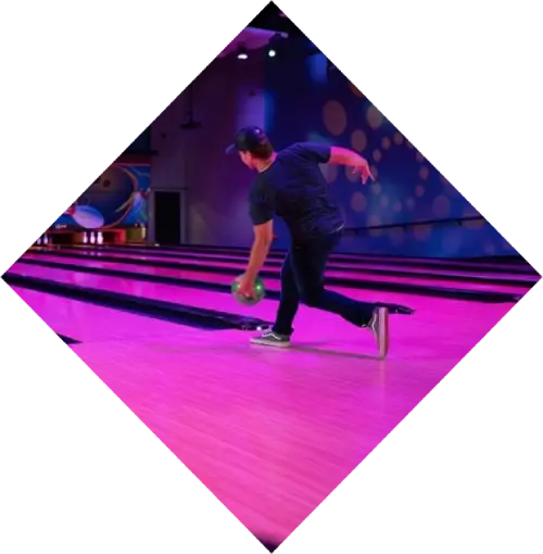 A man bowling in the vibrant Harrah's Cherokee Valley River Casino alley, with colorful lighting in the background, captured in a triangular frame. He is in motion, focused on releasing the ball.