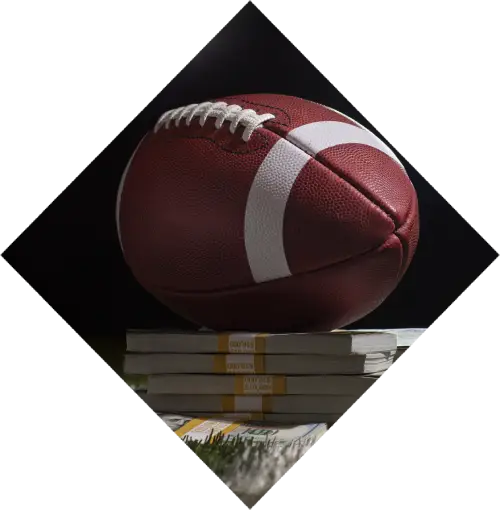A football rests on a reflective surface, partly overlapping a stack of various books, blending sports and education themes, set against a dark background in the Harrah's Cherokee Valley River casino.